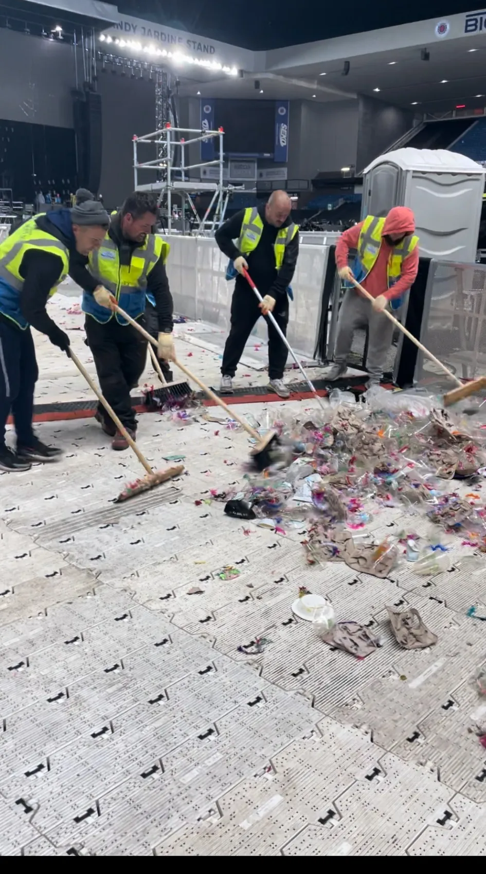 SWS event-cleaning operatives clearing waste from the floor at Ibrox Stadium